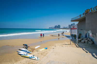 People on beach against clear blue sky