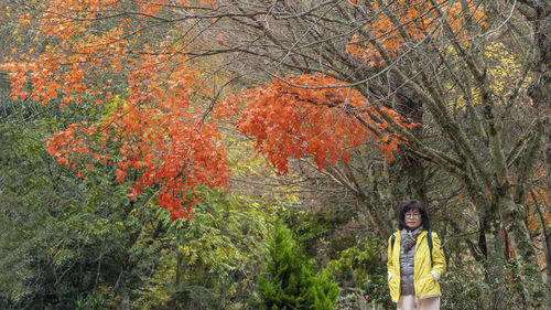 Portrait of woman standing amidst trees during autumn