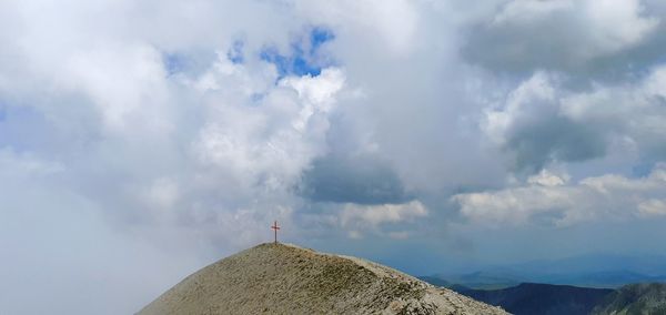 Low angle view of cross on mountain against sky