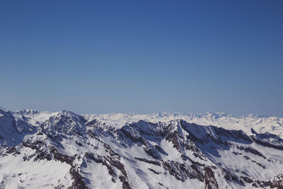 Scenic view of snowcapped mountains against clear blue sky