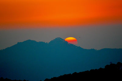 Scenic view of silhouette mountain against orange sky at sunset