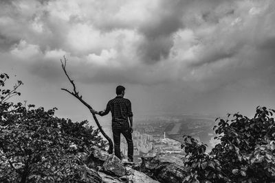 Rear view of man standing by plants against sky