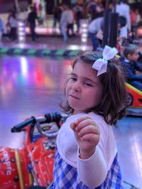 Cute girl sitting on toy car at amusement park