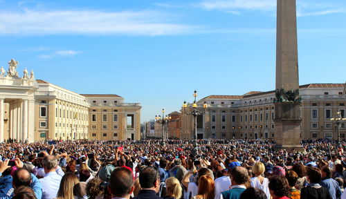 Crowd in city against sky