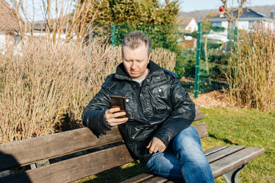 A man sits on a bench and uses a mobile phone. wireless technologies. communication at a distance