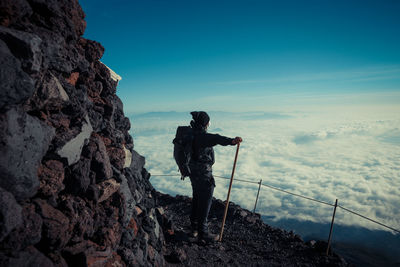 Hiker standing on mountain against sky