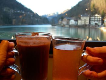 Close-up of hand holding drink hot chocolate and hot tea in hands near window with view outside