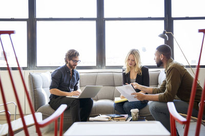 Colleagues planning while sitting by window in office