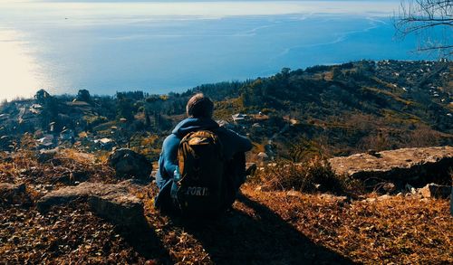 Rear view of man sitting on mountain