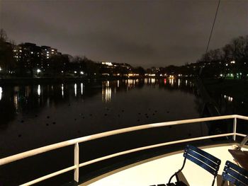 Illuminated city by river against sky at night