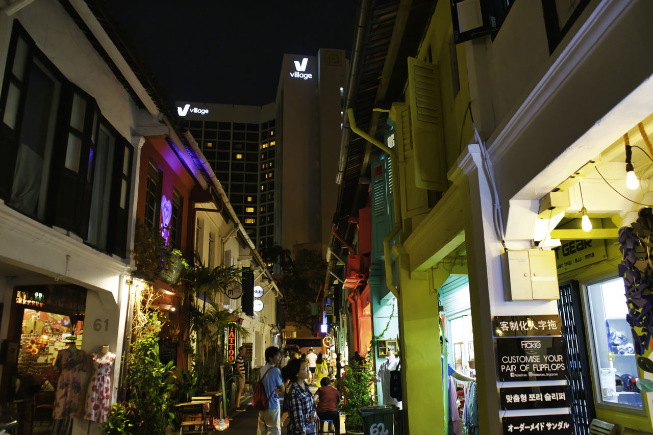 PANORAMIC VIEW OF ILLUMINATED STREET AMIDST BUILDINGS IN CITY