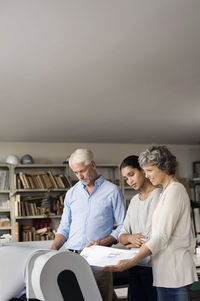 Male and female interior designers analyzing blueprint in office