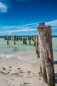 Wooden posts on beach against sky
