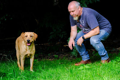 Full length of man and dog looking at grass