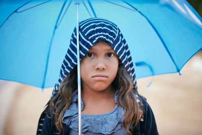 Portrait of girl with umbrella wearing raincoat during rainy season