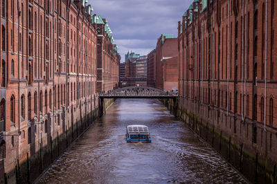 Canal amidst buildings against sky in city