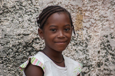 Portrait of girl smiling against wall