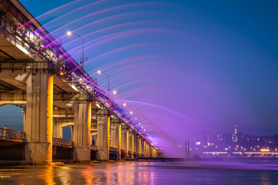 Illuminated bridge over river at night