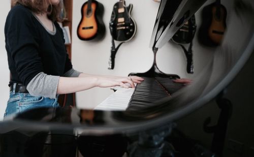 Midsection of woman playing piano at home