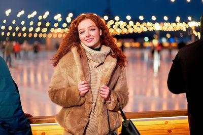 Portrait of smiling young woman standing outdoors during winter