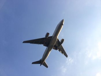 Low angle view of airplane against blue sky