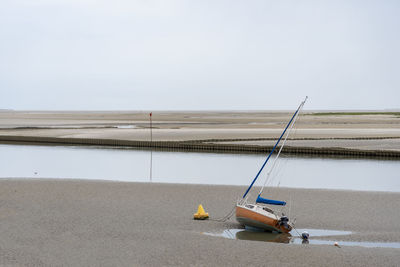 Sailboat moored on beach against clear sky