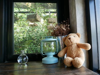 Teddy bear and lantern on table at home