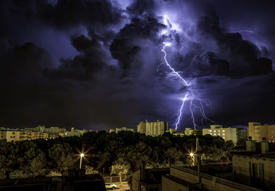 Lightning over illuminated buildings in city at night