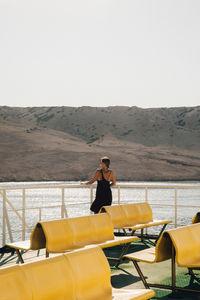 Woman standing by railing against clear sky