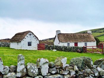 Houses on field against cloudy sky