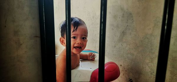 Portrait of cute boy peeking through window at home