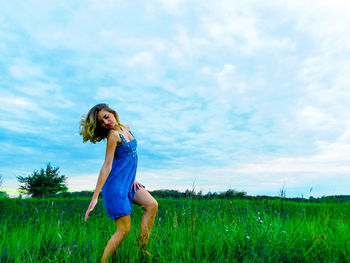 Portrait of young woman standing on field against sky