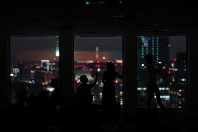 Silhouette people standing in illuminated building at night