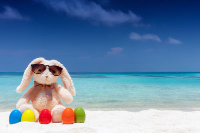 Toy with easter eggs at beach by sea against sky