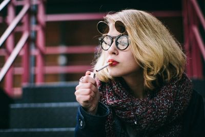 Portrait of young woman smoking cigarette outdoors