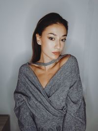 Portrait of young woman standing against wall