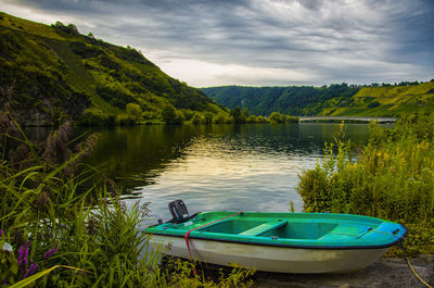 Boat moored at lakeshore against sky