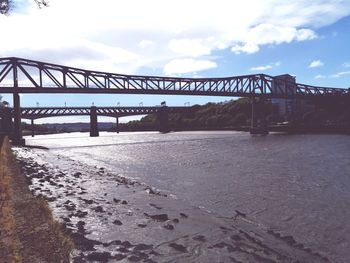 Bridge over calm river against sky