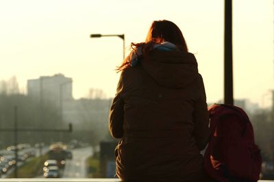 Rear view of woman standing against sky during sunset