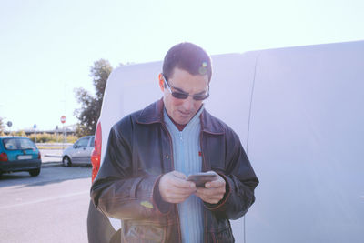 Young man using smart phone against clear sky