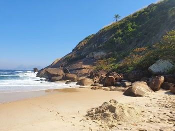 Rock formation on beach against clear sky