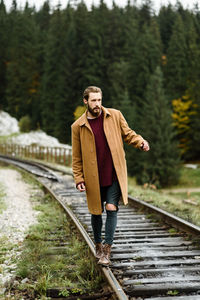 Full length of young man standing on railroad track
