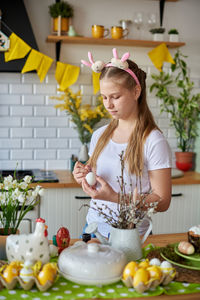 Girl 12 years old paints eggs for easter in the kitchen
