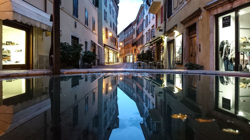 Reflection of buildings in puddle on street