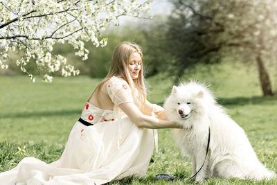 Side view of young woman with dog on field