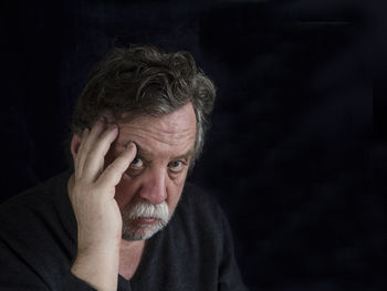 Close-up of depressed mature man against black background