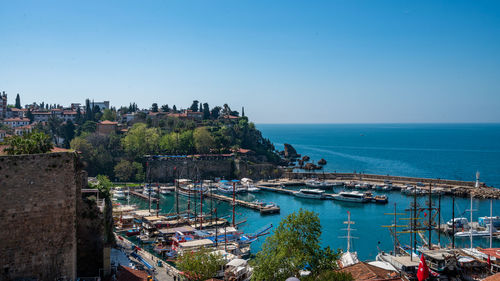 High angle view of townscape by sea against clear blue sky