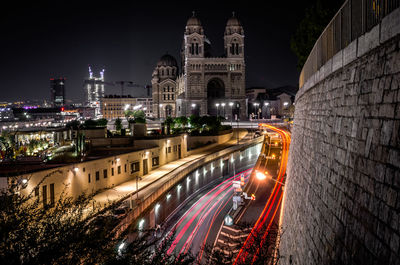 Light trails on city against sky at night