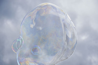 Low angle view of bubble against cloudy sky