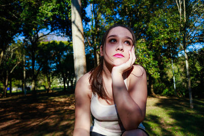 Thoughtful young woman against tree at park